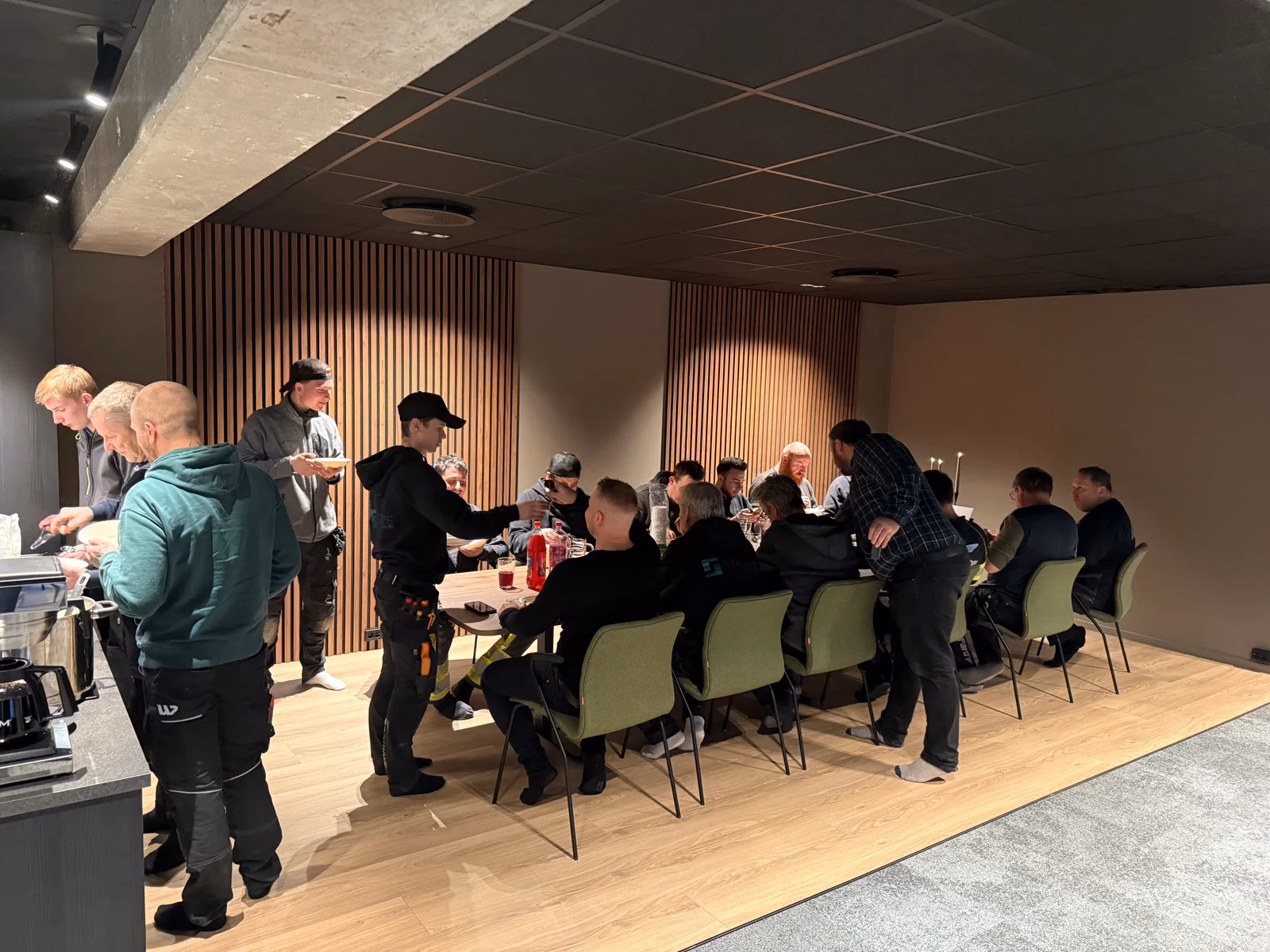 Kolleger forsyner seg med mat og sitter sammen rundt et langbord.